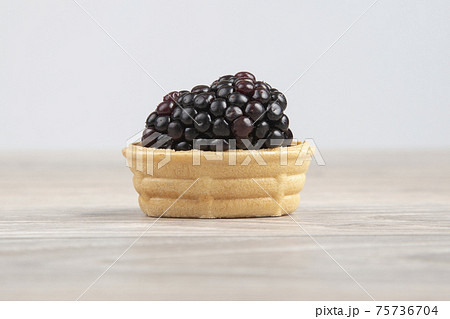 Blackberries in a waffle basket on a light background. Healthy and vitamin food. Blackberries in a waffle basket on a light background. Healthy and vitamin food. 75736704