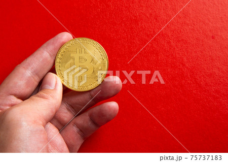 Hand holding a bitcoin on red background 75737183