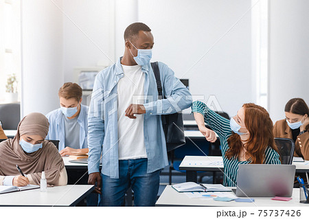 Diverse multicultural people wearing face masks greeting and bumping elbows Diverse multicultural people wearing face masks greeting and bumping elbows 75737426