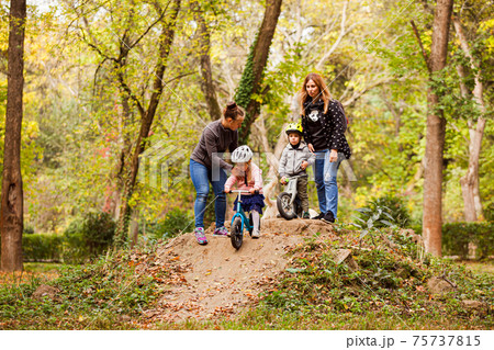 Mothers teaching and supporting their kids on bike ride Mothers teaching and supporting their kids on bike ride 75737815
