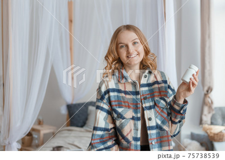 Beautiful blond girl Holding white Bottle With Pills In Hand. Diet. Nutrition. Healthy Eating, Lifestyle. Headache concept, Mockup packaging 75738539