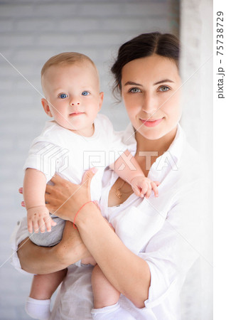 Mother and child in a white room. Mom and baby boy in diaper pla 75738729