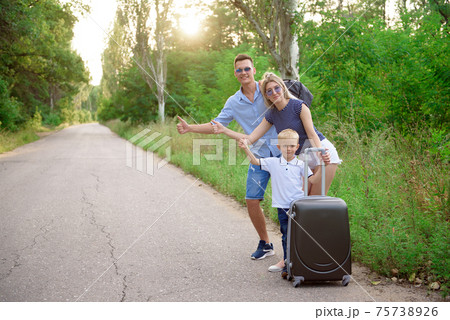 Young family traveller hitch hiking on empty road Young family traveller hitch hiking on empty road 75738926