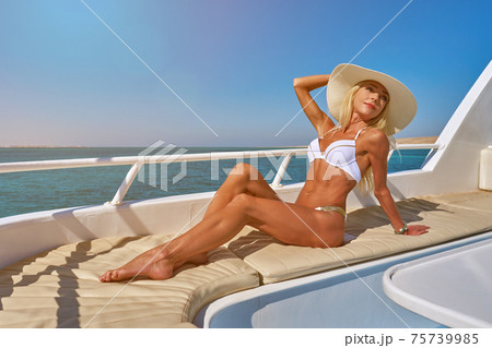 Young woman on the deck of a boat in open sea at sunny summer day 75739985