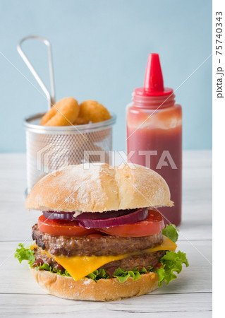 Cheeseburger with beef,tomato, lettuce, onion and onion rings on wooden table 75740343