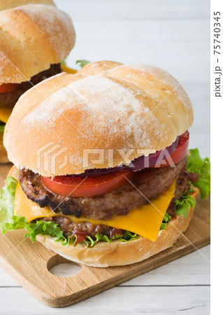 Cheeseburger with beef,tomato, lettuce and onion on wooden table 75740345
