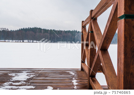 Winter Landscape of a Frozen Lake and Wooden Fishing Bridge Covered with Snow 75740865