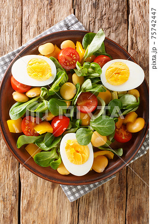 Fresh salad of lupine beans, eggs, tomatoes and Valerianella locusta close-up in a plate. vertical top view Fresh salad of lupine beans, eggs, tomatoes and Valerianella locusta close-up in a plate. vertical top view 75742447