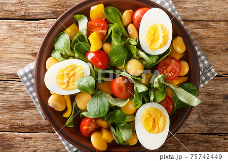 Vitamin delicious salad of lupine beans, boiled eggs, tomatoes and common cornsalad close-up in a plate. horizontal top view Vitamin delicious salad of lupine beans, boiled eggs, tomatoes and common cornsalad close-up in a plate. horizontal top view 75742449