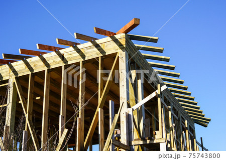 new modern wooden house under construction, blue sky background new modern wooden house under construction, blue sky background 75743800