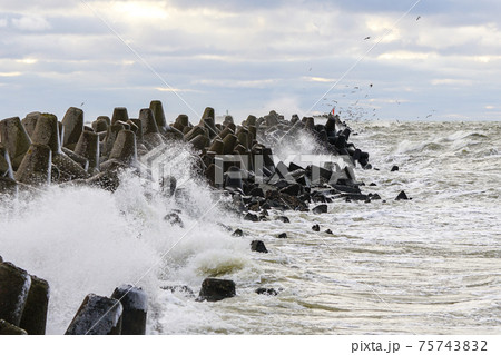 storm on the Baltic coast, waves hitting the breakwater concrete tetrapods 75743832