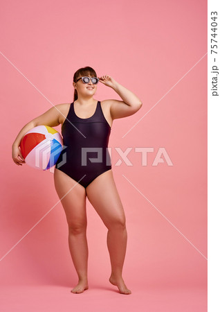Overweight woman poses in swimsuit and sunglasses Overweight woman poses in swimsuit and sunglasses 75744043