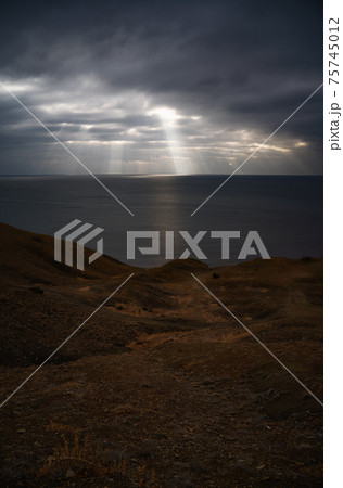 Sun rays make their way through dramatic clouds. Weather turns bad in the evening. Beautiful seascape. Vertical image Sun rays make their way through dramatic clouds. Weather turns bad in the evening. Beautiful seascape. Vertical image 75745012