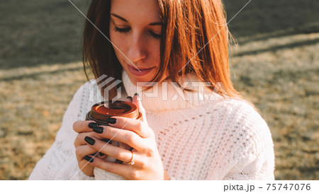Tea drinking woman. Happy young girl with cup of coffee in sun sitting outdoor. Cup of Hot Beverage. 75747076