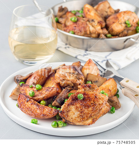 Chicken with potatoes, mushrooms and green peas, on a white plate and in metal pot, square format Chicken with potatoes, mushrooms and green peas, on a white plate and in metal pot, square format 75748505