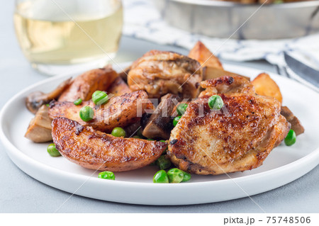 Chicken with potatoes, mushrooms and green peas, on a white plate and in metal pot, horizontal 75748506