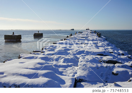 winter seascape, port entrance with snow covered concrete breakwater winter seascape, port entrance with snow covered concrete breakwater 75748553