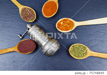 Set of different aromatic spices and spice mill on black slate. Top view Set of different aromatic spices and spice mill on black slate. Top view 75748695