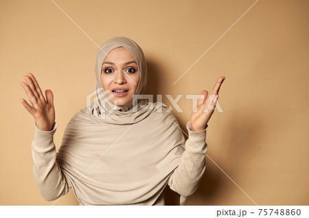 Arabic Muslim woman wearing traditional clothing and covered head in hijab gesturing with hands and expressing anger and frustration 75748860
