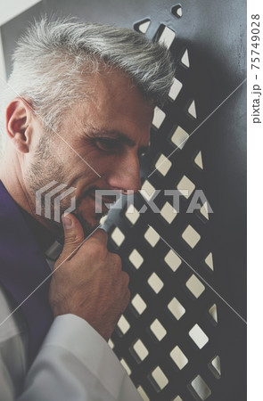Confession box and priest listening to the sins of the faithful. Confession box and priest listening to the sins of the faithful. 75749028
