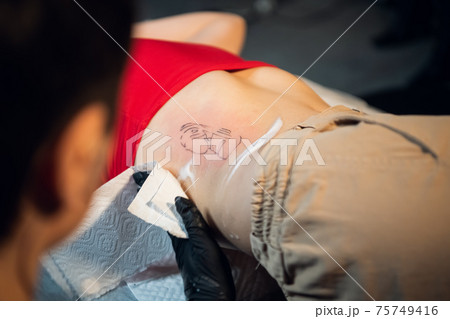 Filling the tattoo is finished, the master treats the skin with a wound-healing foam Filling the tattoo is finished, the master treats the skin with a wound-healing foam 75749416