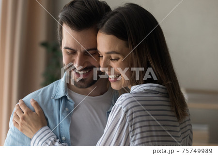 Close up happy woman and man hugging, enjoying tender moment 75749989