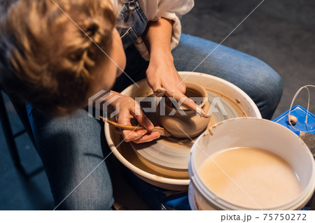 the process of modeling a clay vase shows a young potter in his Studio. 75750272