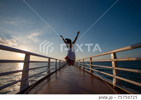 橋でジャンプする女の子の後ろ姿の写真素材