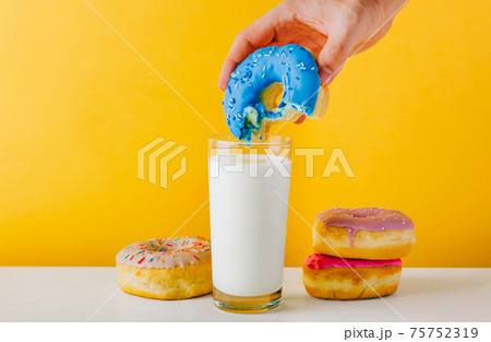 Adult man hand dipping donut into milk Adult man hand dipping donut into milk 75752319