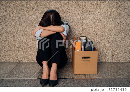 Young woman with box of stuff after losing job 75753456