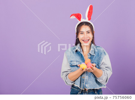 woman smiling wearing rabbit ears and denims hold colorful Easter eggs gift on hands woman smiling wearing rabbit ears and denims hold colorful Easter eggs gift on hands 75756060
