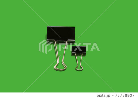 two small and big paper clips on a green surface two small and big paper clips on a green surface 75758907