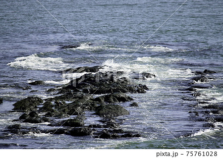 夏の海 岩に打ち寄せる波の写真素材