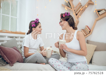 Woman and girl in curlers with cups communicating 75762528