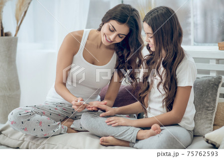 Mom is painting fingernails on happy girls hand Mom is painting fingernails on happy girls hand 75762593