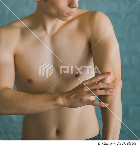 腕の筋肉を触る男性 75763968