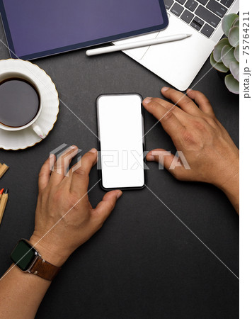 Male hands working on smartphone with mock up screen on dark workspace Male hands working on smartphone with mock up screen on dark workspace 75764211