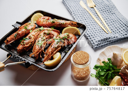 Grilled large queen shrimps with lemon and spices on the grill pan 75764817