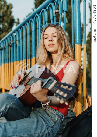 Creative hobbies, guitar lessons, playing musical instruments. Acoustic guitars for beginners. Young blonde woman with Acoustic guitar outdoor Creative hobbies, guitar lessons, playing musical instruments. Acoustic guitars for beginners. Young blonde woman with Acoustic guitar outdoor 75764891
