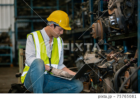 engineering man worker wear uniform and helmet using laptop checking automotive parts in warehouse. 75765081