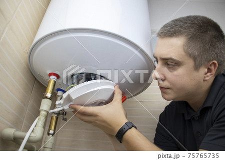 The boiler repairman checks the electronics in the water heater. Professional assistance and technical support concept 75765735