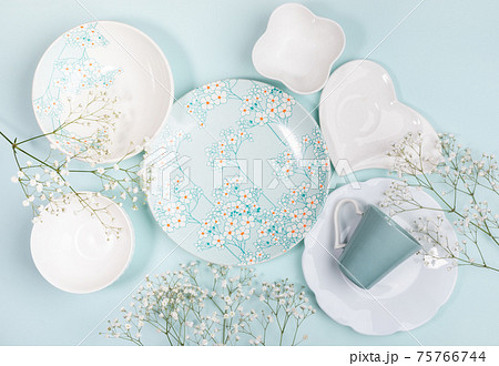 Spring creative festive composition of lot of beautiful dishware white and with floral decor and white flowers on light blue background. Top view. Flat lay. Easter. Mother's Day. Copy space. Mock up. 75766744