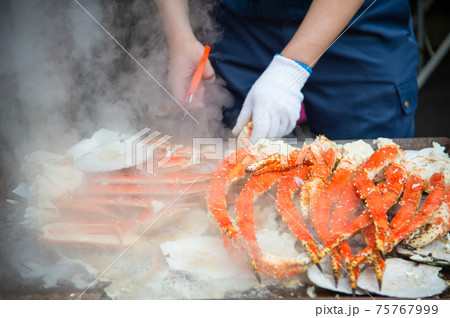 Tokyo, Japan Street in Tsukiji outer market in Ginza with closeup retail sample display of cooked red crab lobster legs white meat. 75767999
