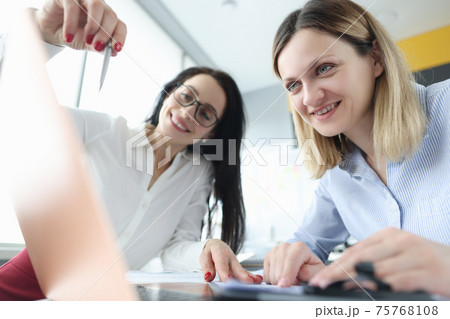Two businesswoman are discussing business processes by demonstrating them on laptop 75768108