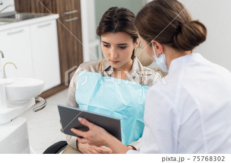 A female patient with a doctor using a tablet in a dental clinic A female patient with a doctor using a tablet in a dental clinic 75768302