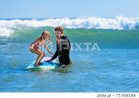 Young surfer learn to ride on surfboard with surf instructor Young surfer learn to ride on surfboard with surf instructor 75768588