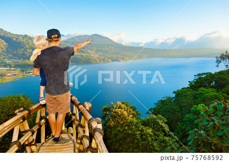 Father with child look at amazing tropical lake in mountains Father with child look at amazing tropical lake in mountains 75768592