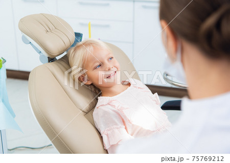 A cute little girl at the dentist's office and a doctor in the f 75769212