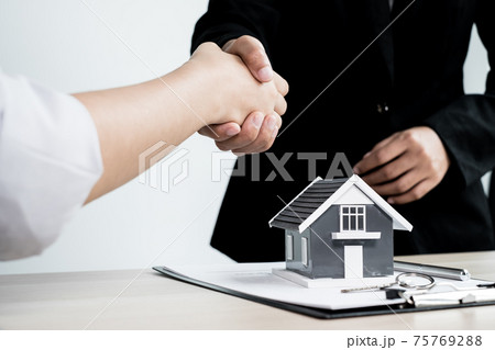 Businessmen and brokers real estate agents shake hands after completing negotiations to buy houses insurance and sign contracts. Home insurance concept Businessmen and brokers real estate agents shake hands after completing negotiations to buy houses insurance and sign contracts. Home insurance concept 75769288