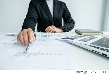 The hands of a male businesswoman are analyzing and calculating the annual income and expenses in a financial graph that shows results To summarize balances overall in office 75769311